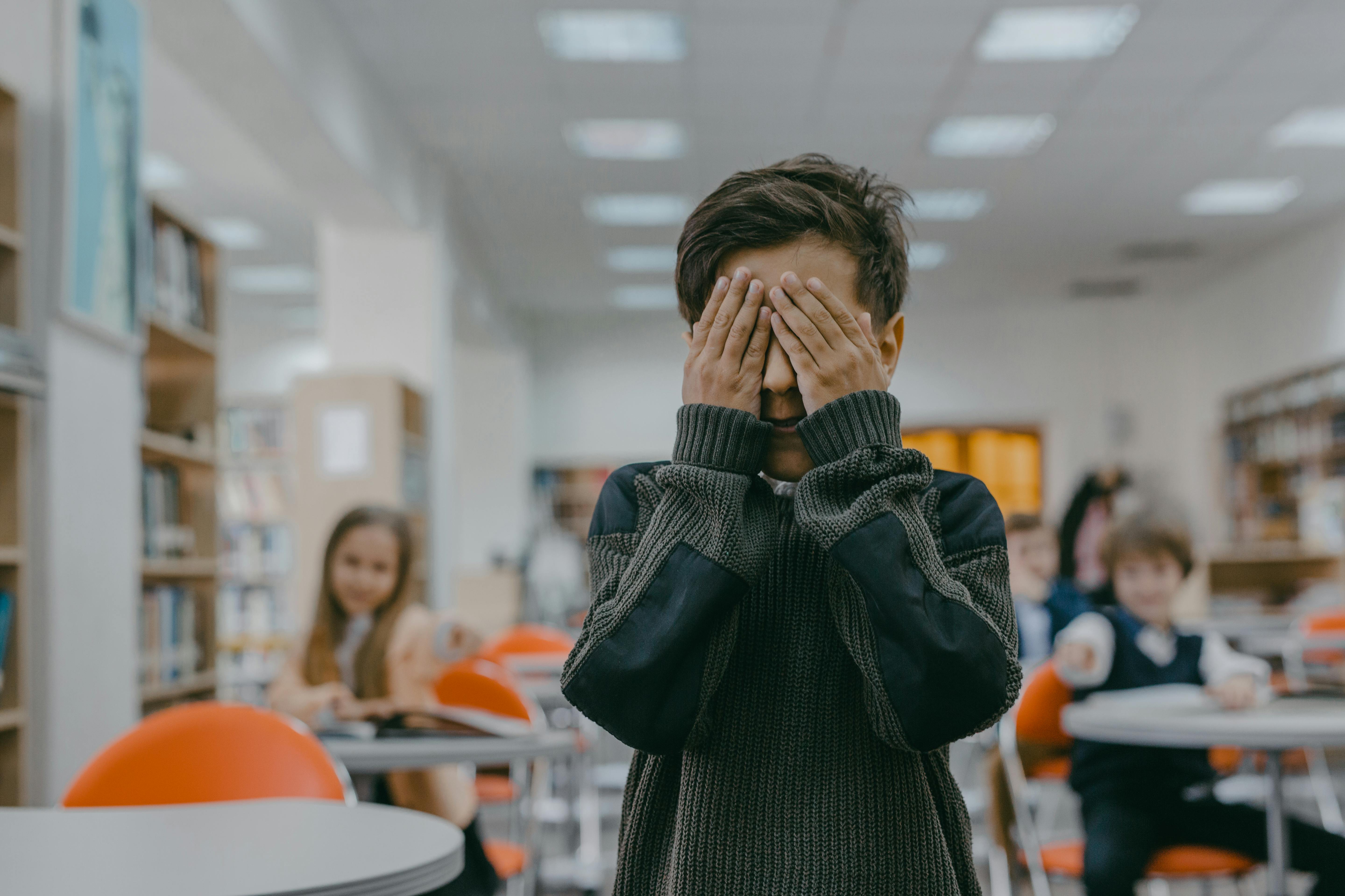 Boy covering his face and stressed out in a clasroom